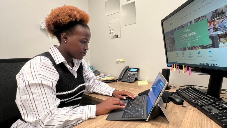 A woman looks focused as she sits at a desk working on a tablet with a keyboard attached to it.