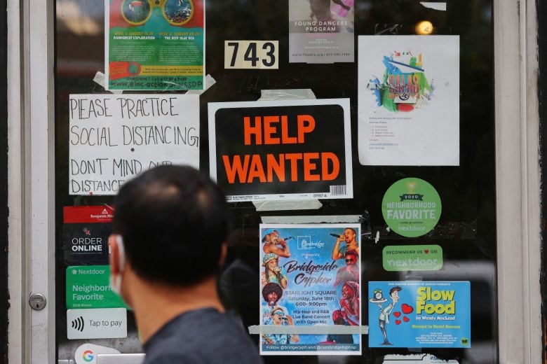 A person walks in front of a door which has signs reading 