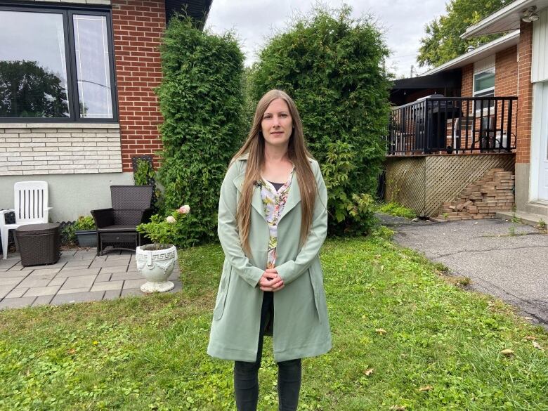 Meredith Bedard wearing a green knee-length jacket on her lawn.