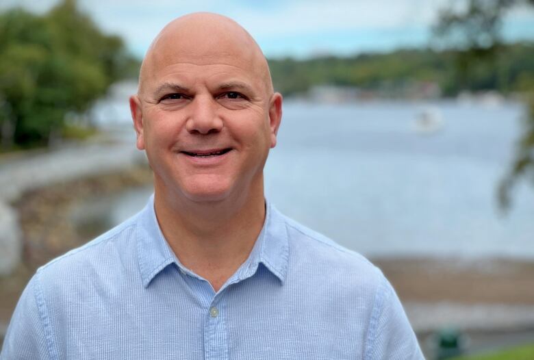 A man stands in front of a body of water.