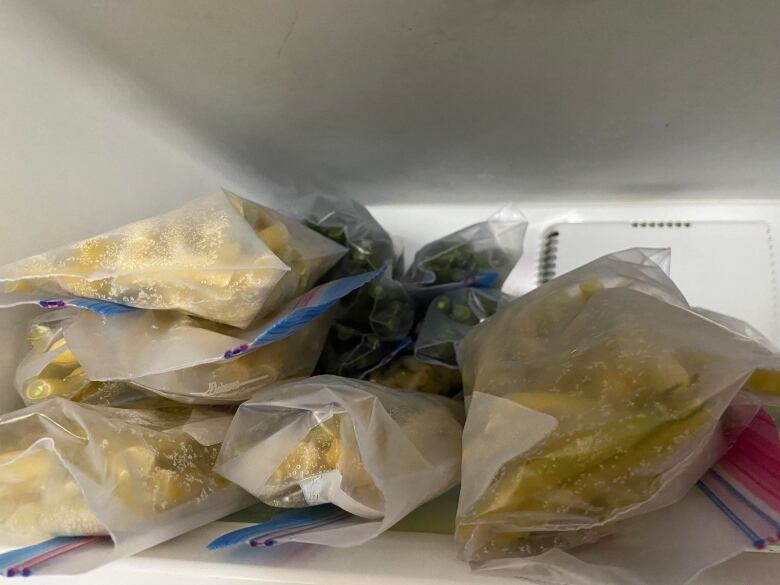 Clear plastic bags of green and yellow beans stacked in a freezer