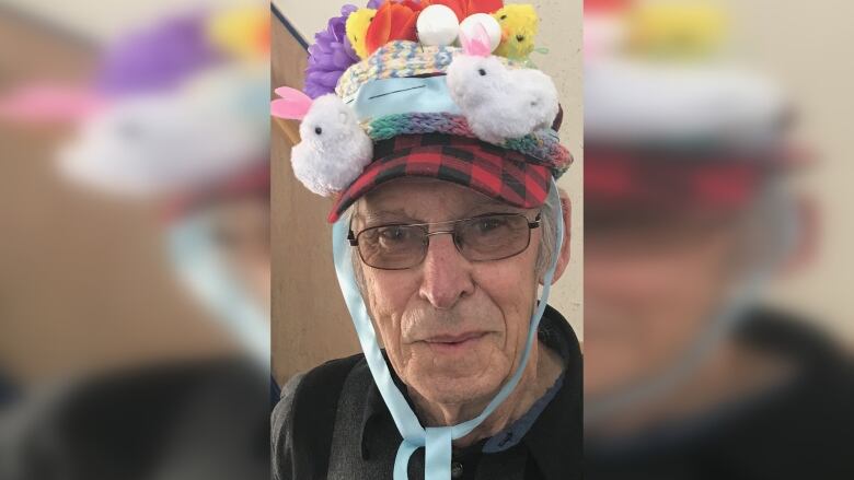 An elderly man wearing a hat with colourful flowers and animals