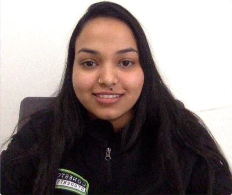 Sana Banu smiles in a selfie. She is wearing a shirt that says 'Conestoga Student', and has a gold nose ring.