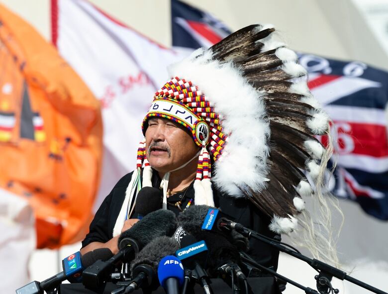 Brian Hardlotte, Grand Chief of the Prince Albert Grand Council, speaking at a press conference in an Indigenous headdress. 