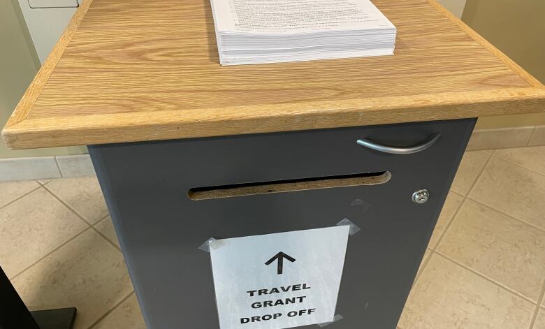 A box in the foyer of the hospital in Wawa, Ont. has a sign reading 'travel grant drop off' and there is a stack of application forms on the top. 