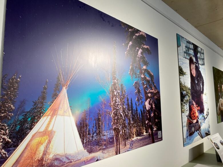 A photograph of Northern lights above a teepee in the winter forest hangs on a wall.