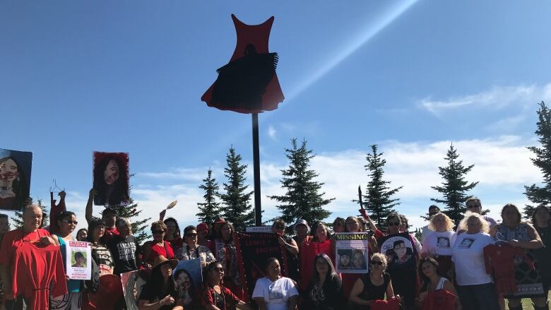 A group of people surround the Journey of Hope monument in Prince George, B.C.