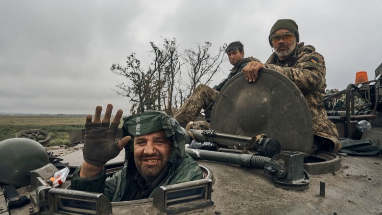 A man waves from a tank