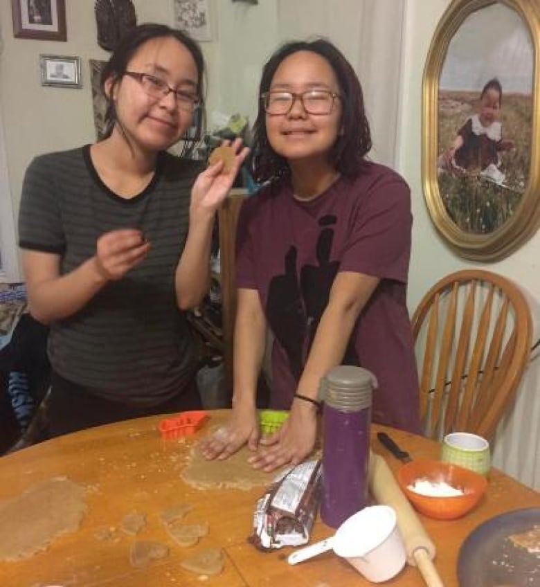 Two girls make cookies at a kitchen table 