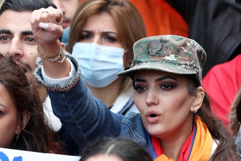 A woman protests by holding up her fist in a crowd