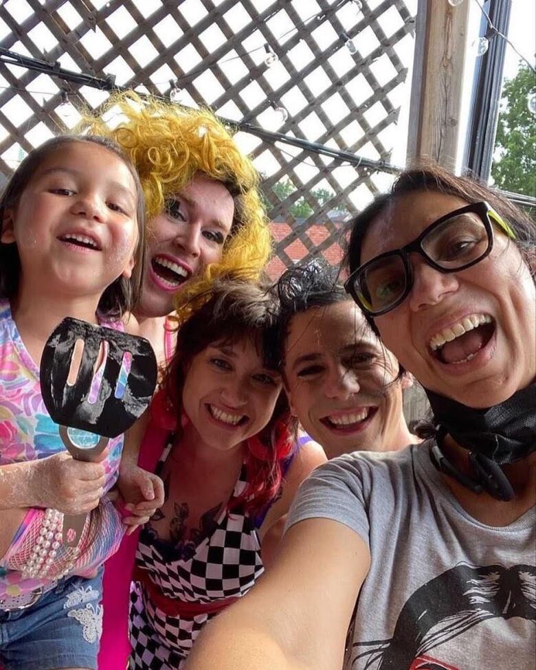 A little girl smiles next to four smiling adults. 