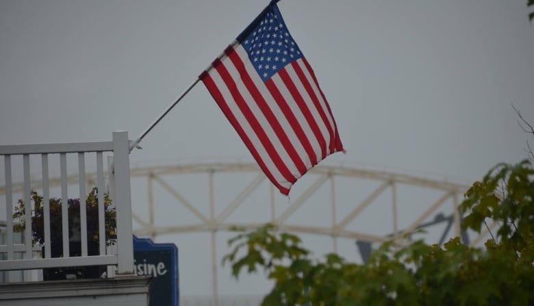 An American flag hangs along Portage Avenue in Sault Ste. Marie, Michigan with the international bridge leading to Canada in the background. 