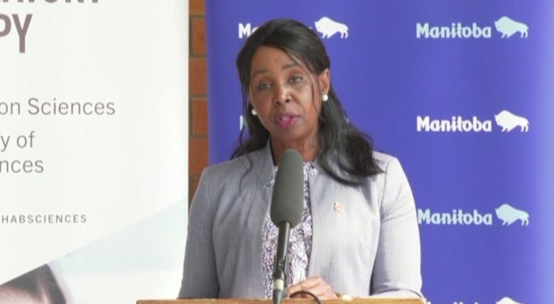 A woman stands in front of a microphone at a podium.