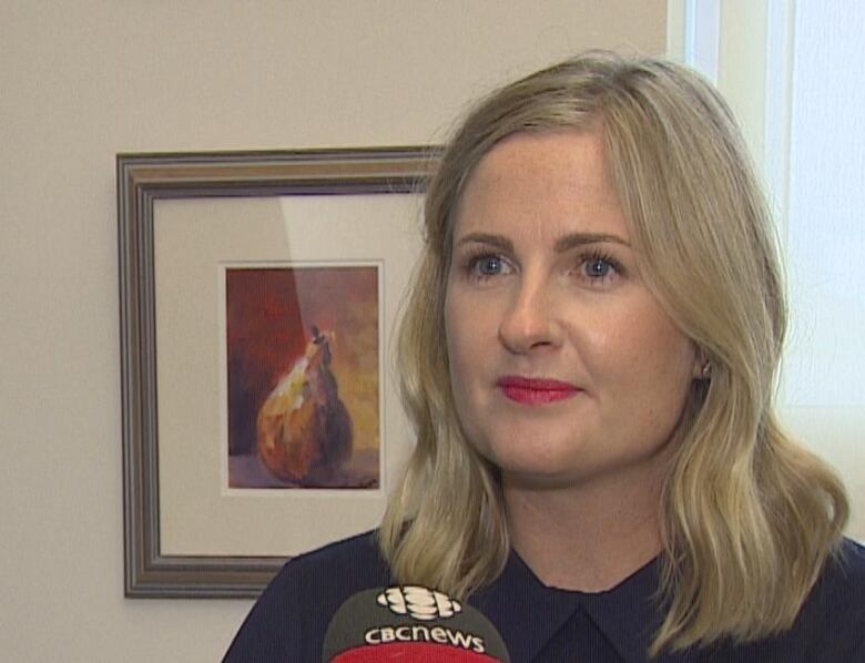 Misty Rossiter with a poster of a pair painting in the background.