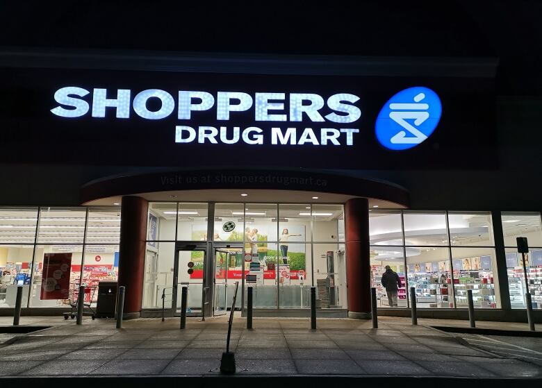 A pharmacy storefront is photographed at night.