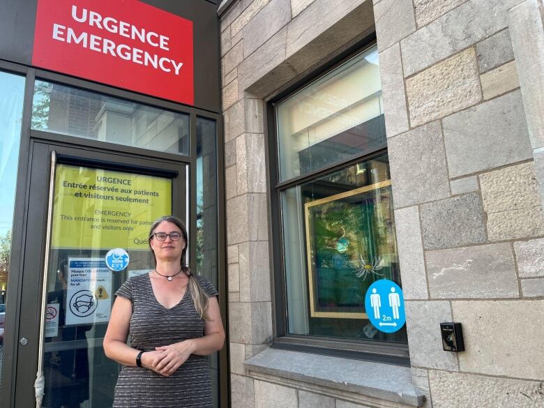 A woman stands in front of a hospital