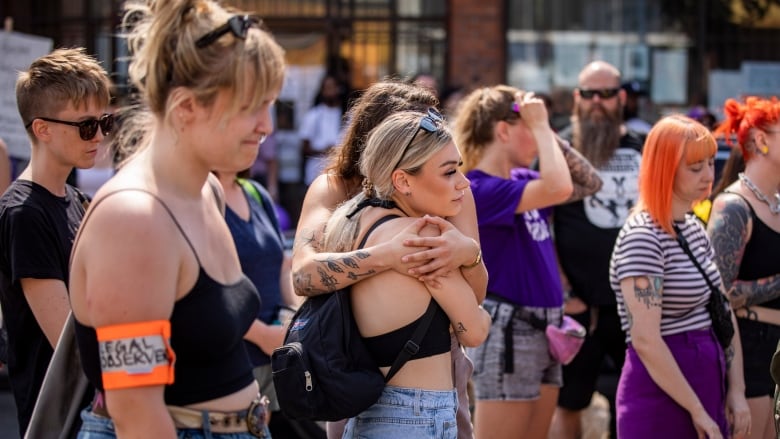 People embrace and grimace at a rally.