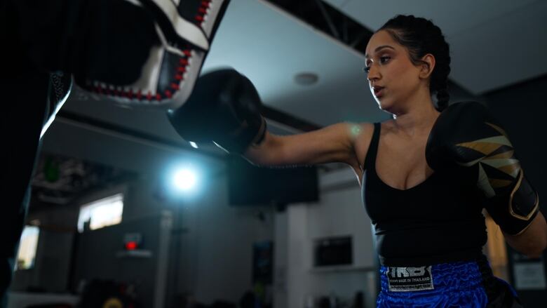 Summan punches a punching bag in training gear.