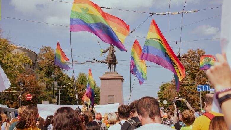 A crowd of people waving rainbow flags. 