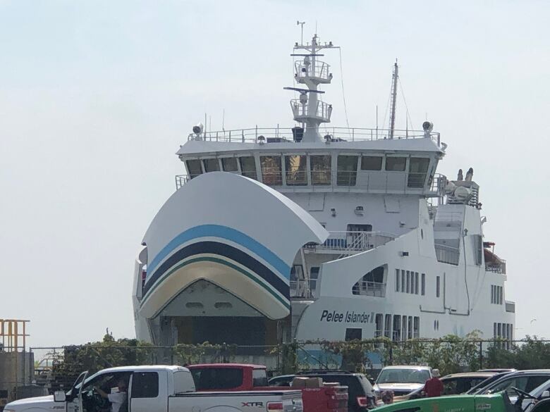 Cars drive onto the back of a docked ferry. 