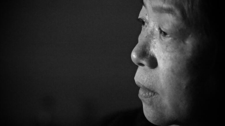 An older Chinese woman is seen in profile in a black-and-white picture.