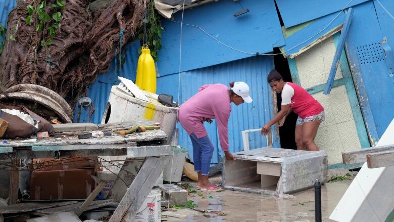 Two people clean up hurricane damage.