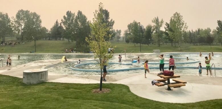 A water park with several children playing as their parents watch them.