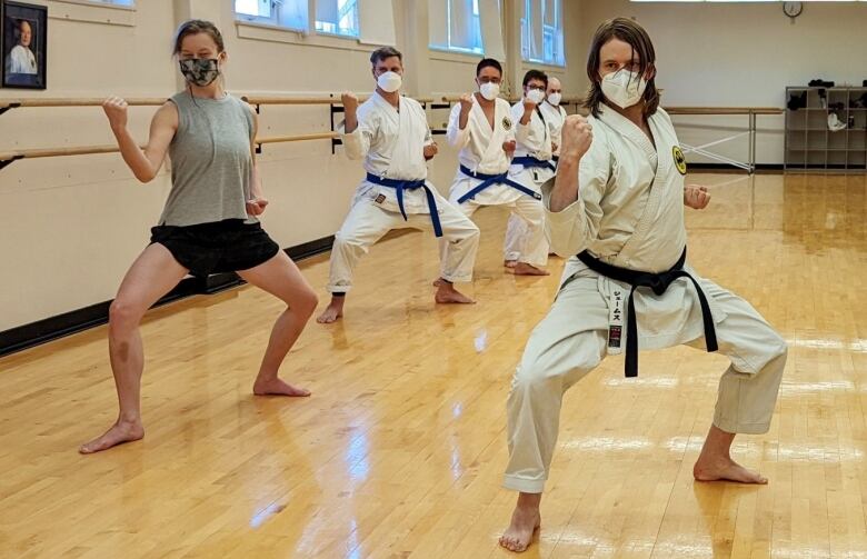 A group of karate students in a gym, all wearing medical masks.