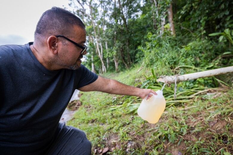 A man collects rainwater in a jug