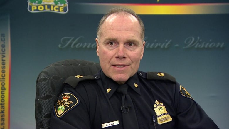 Middle aged man sitting in a chair in his Saskatoon Police Service uniform. 