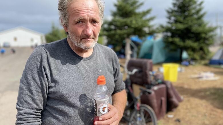 Man stands near a ten holding a Gatorade.