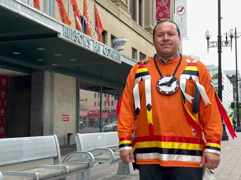 A man wearing an orange ribbon shirt smiles.