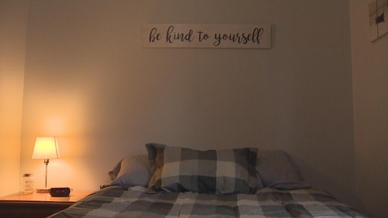 A bed in a dimly lit room, with a sign hanging above that says 