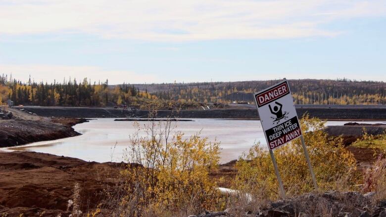 A pond in the fall with a sign that says 