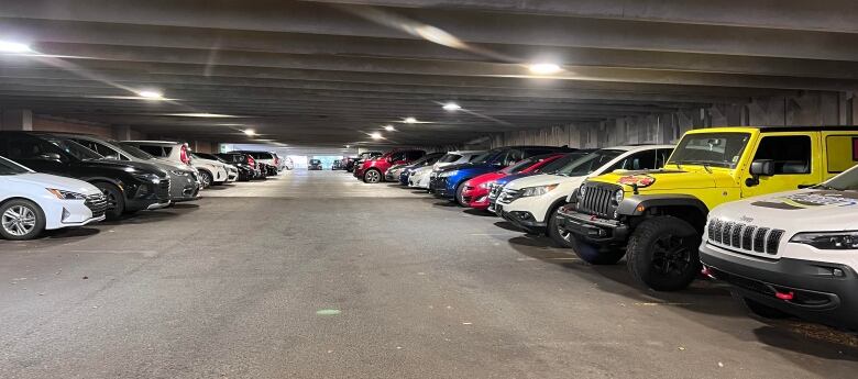 Rows of vehicles parked in indoor parking garage. 