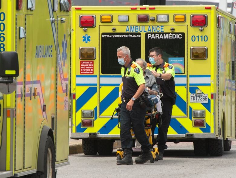 Two paramedics bring a man in stretcher to an ER. 