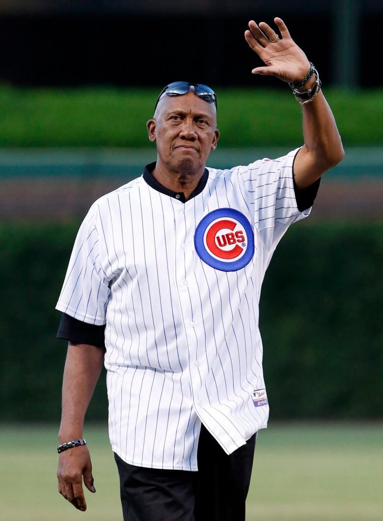 A man waves on a baseball field.