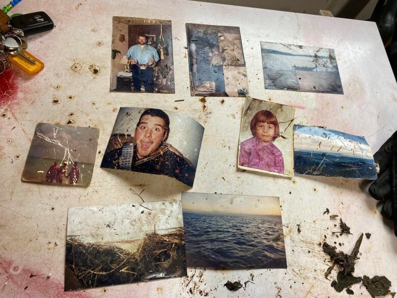 Nine weathered photos sit arranged on a white table.