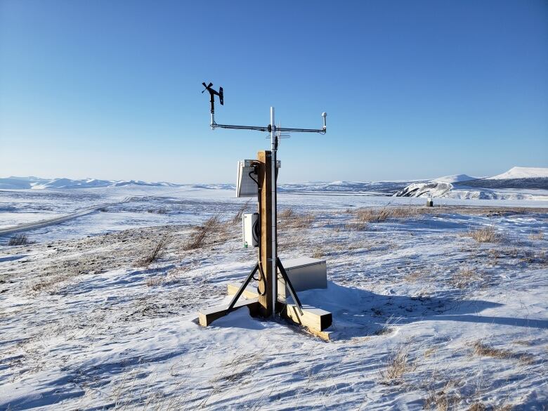 A wind station sitting on a snow covered ground on the Dempster Highway.