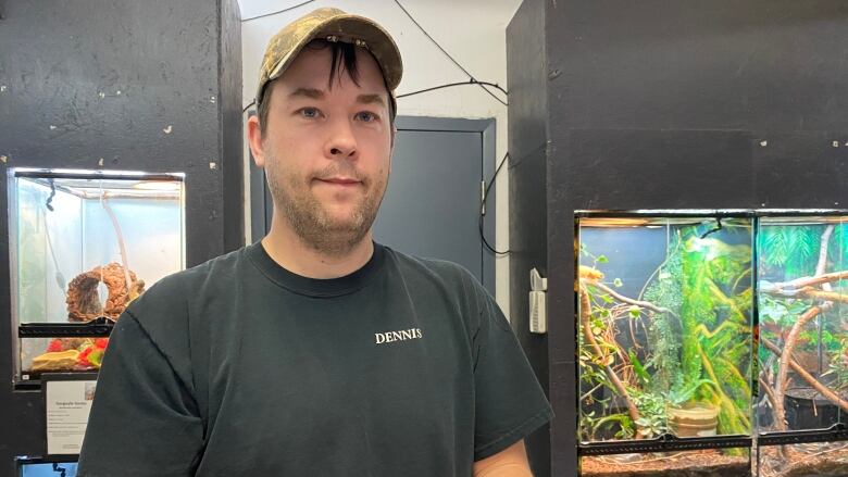 A man with some glass animal enclosures in the background.