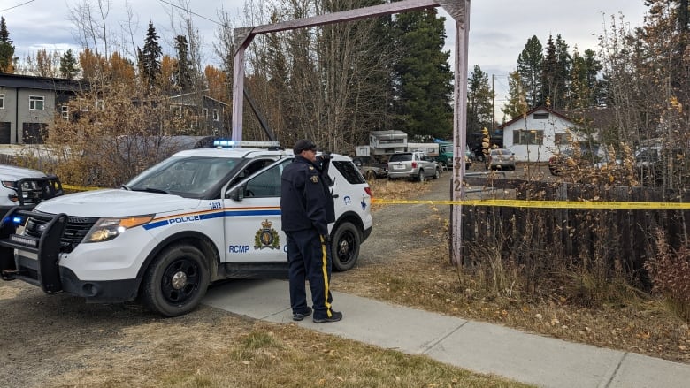 A police officer and police vehicle in front of a home.