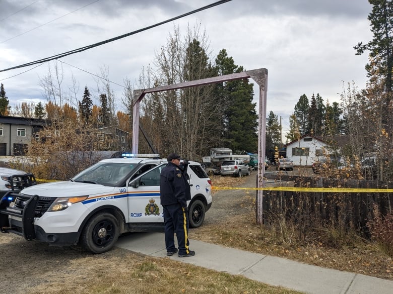 A police officer and police vehicle in front of a home.