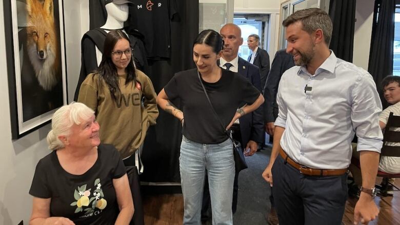 A woman stands at the centre of a small group. People look back and smile at her.