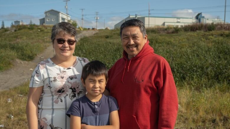 A portrait of three people, two of which are adults and a child is in between them.