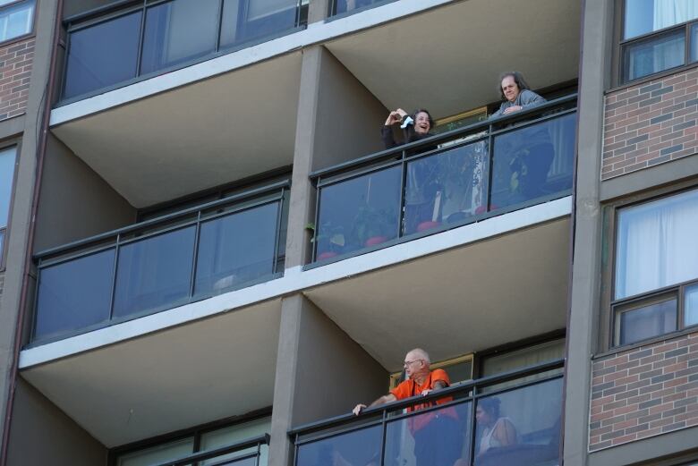 A woman standing in her balcony making a heart shape with her hands.