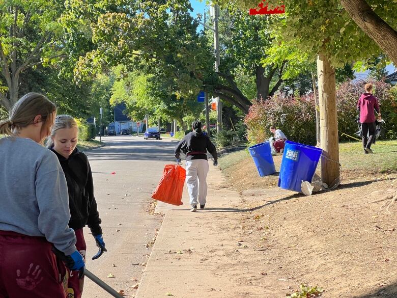 McMaster students with orange bags picking up garbage from the ground.