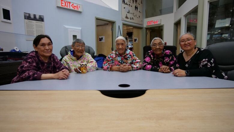 A portrait of five women sitting at a table.