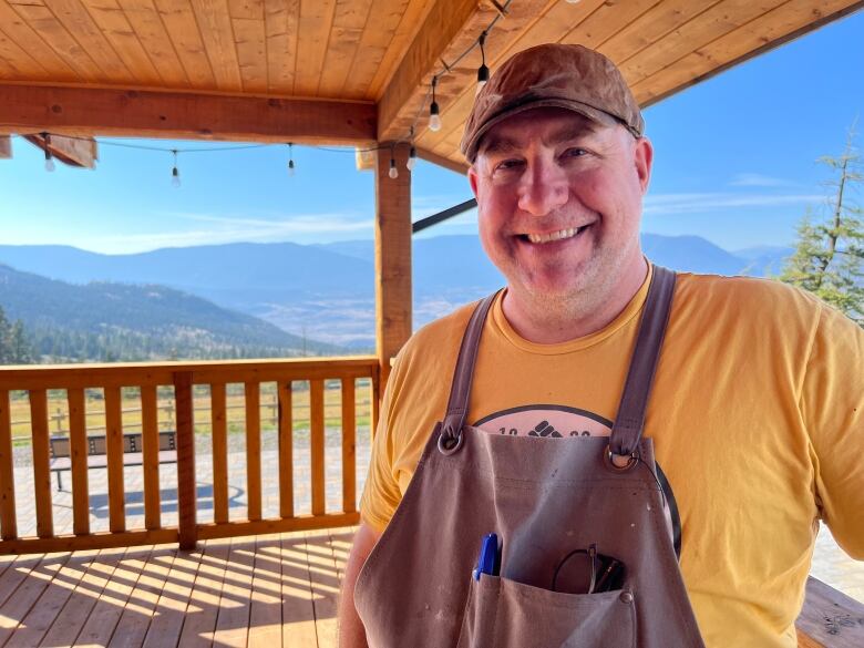 A white man smiles broadly on a patio.