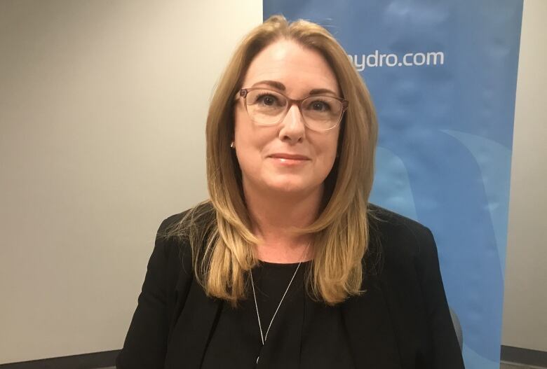 A smiling woman with glasses sits at a table.