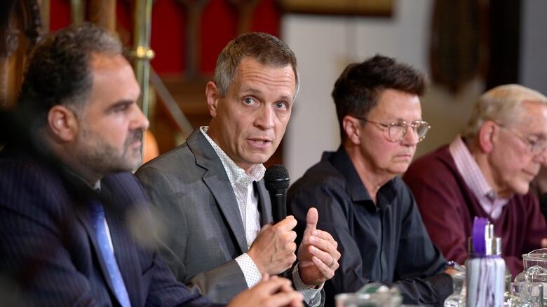 A panel of four people sitting at a table.